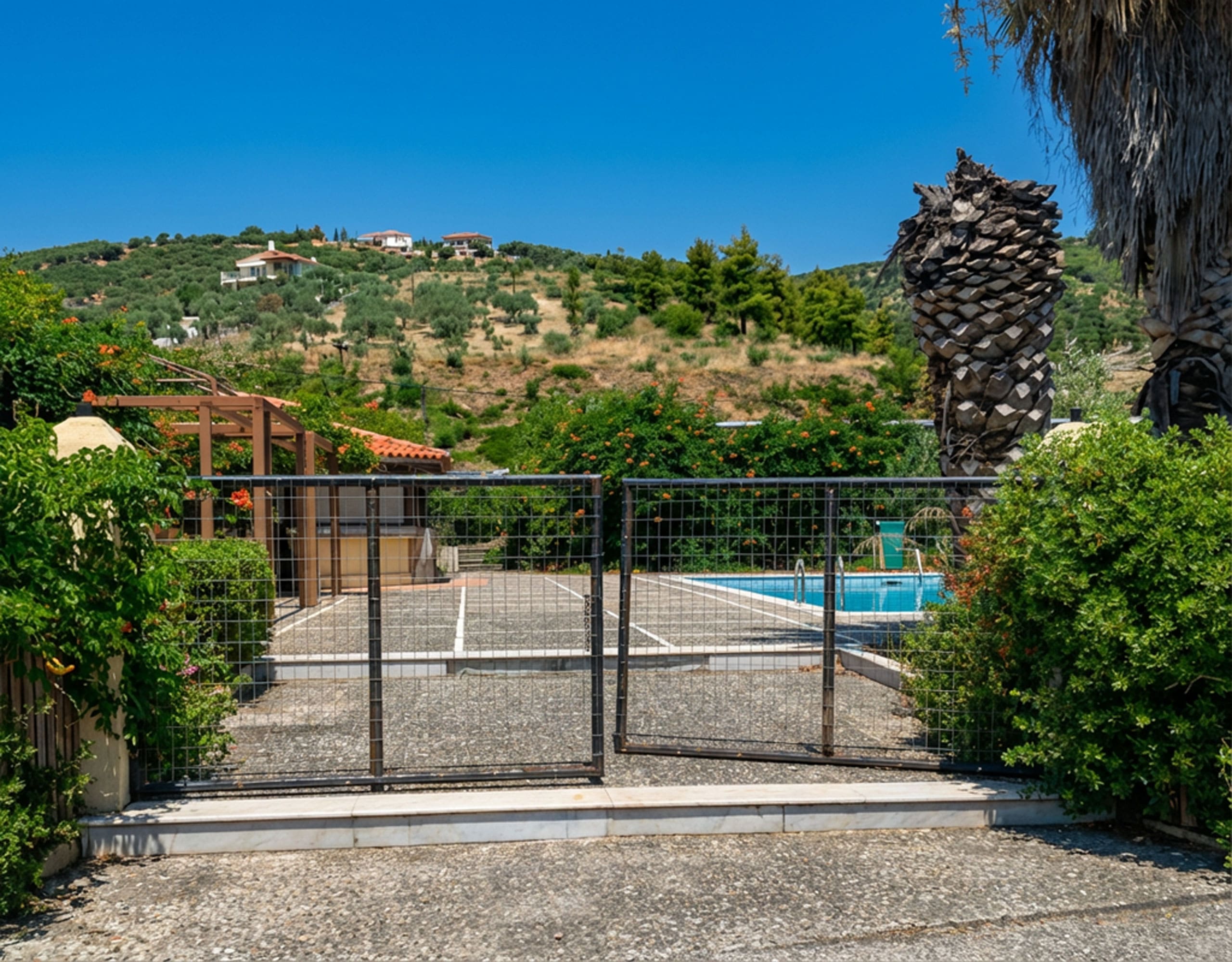 Entrance gate view towards pool and outdoor area at hotel property in Limi, Evia