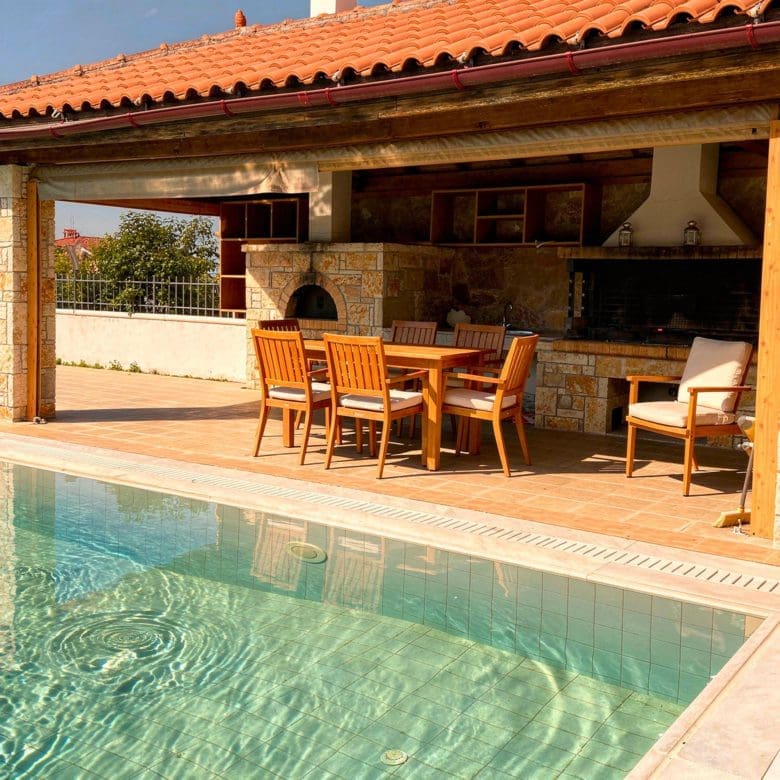 Covered BBQ area with outdoor kitchen and dining space in Eretria