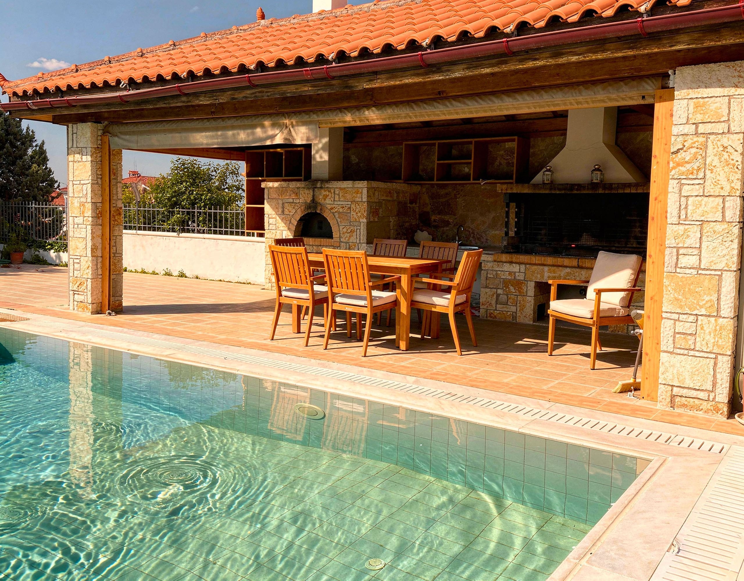 Covered BBQ area with outdoor kitchen and dining space in Eretria